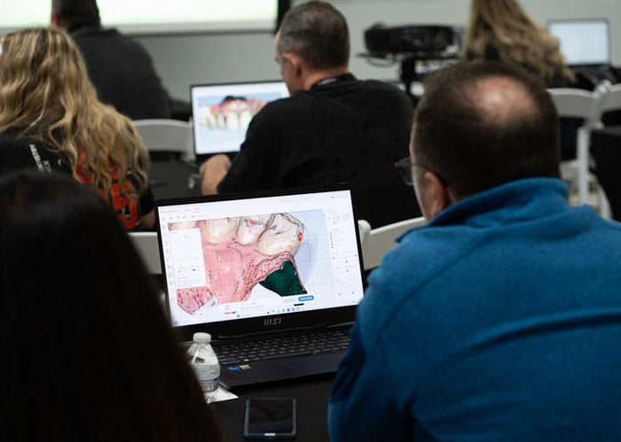 People in a classroom setting with laptops displaying maps.