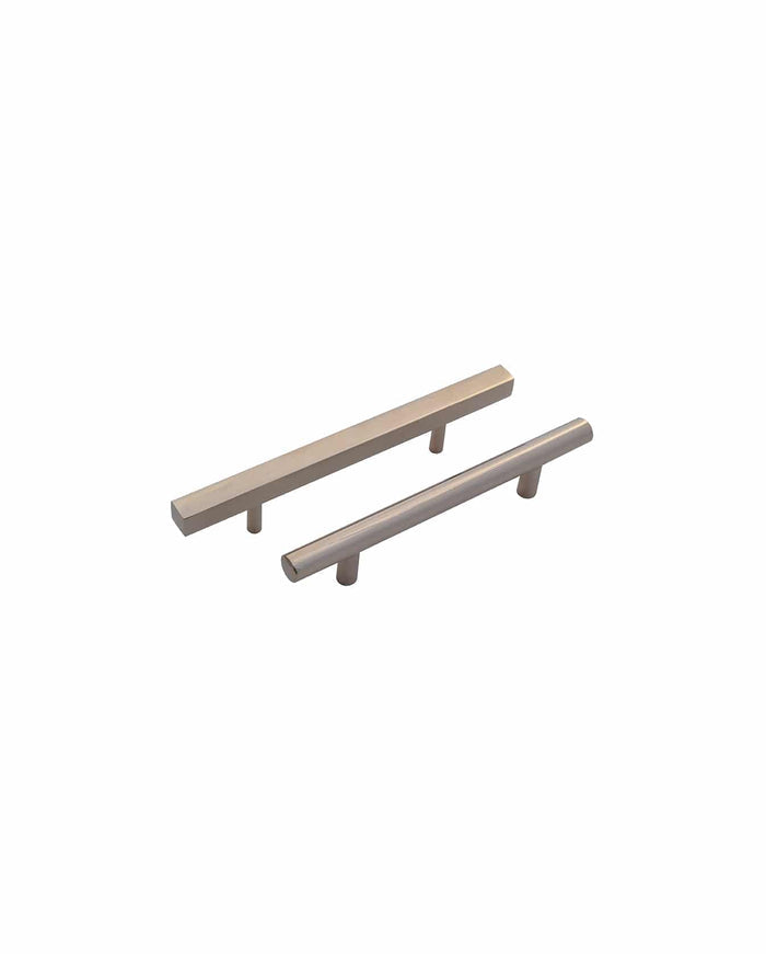 Two Prima Decorative Hardware cabinet handles—a square bar pull with a rectangular design and a solid brass cylindrical pull—both with two mounting posts, displayed on a white background.