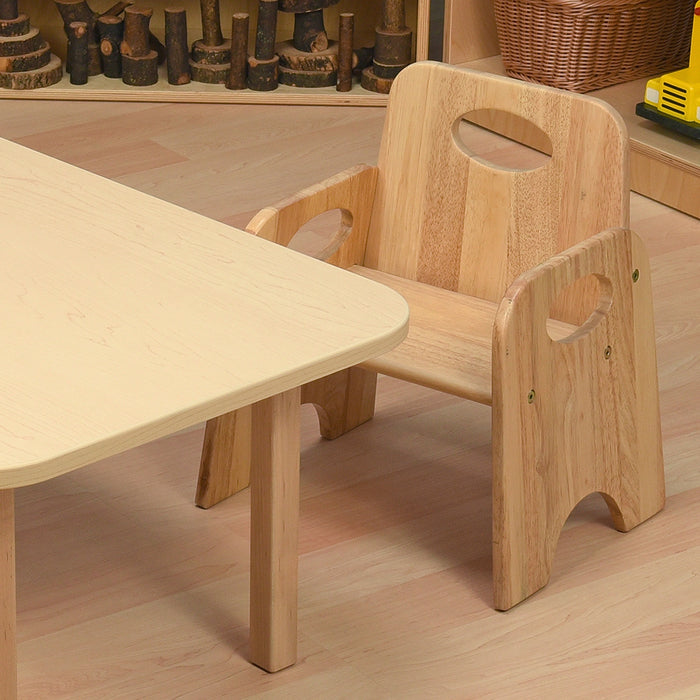 Wooden children's table and chair set on a wooden floor with toys in the background.