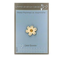 A hand painted wooden button shaped like a daisy with a beige center and a brown border, packaged on a card with 'Lynette Anderson Designs' branding.