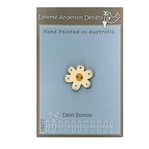 A hand painted wooden button shaped like a daisy with a beige center and a brown border, packaged on a card with 'Lynette Anderson Designs' branding.