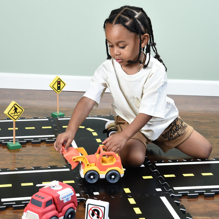 Child playing with toy cars on a road mat with traffic signs