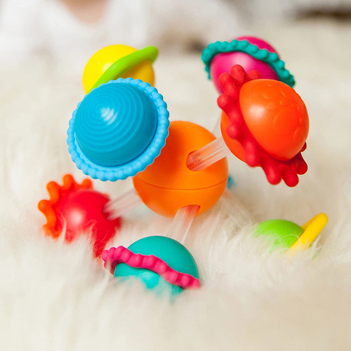 A colorful collection of infant toys with geometric patterns and silicone rings.