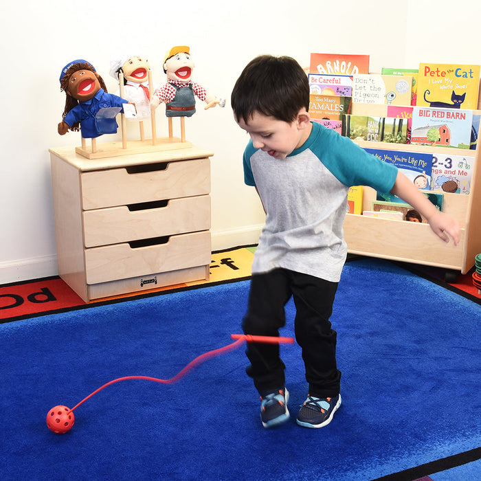 Child playing with red ankle hoop in classroom setting