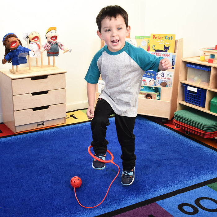 Child playing with red ankle hoop in classroom setting