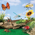 Assorted toy insects and a flower on a grassy area with a blue sky background