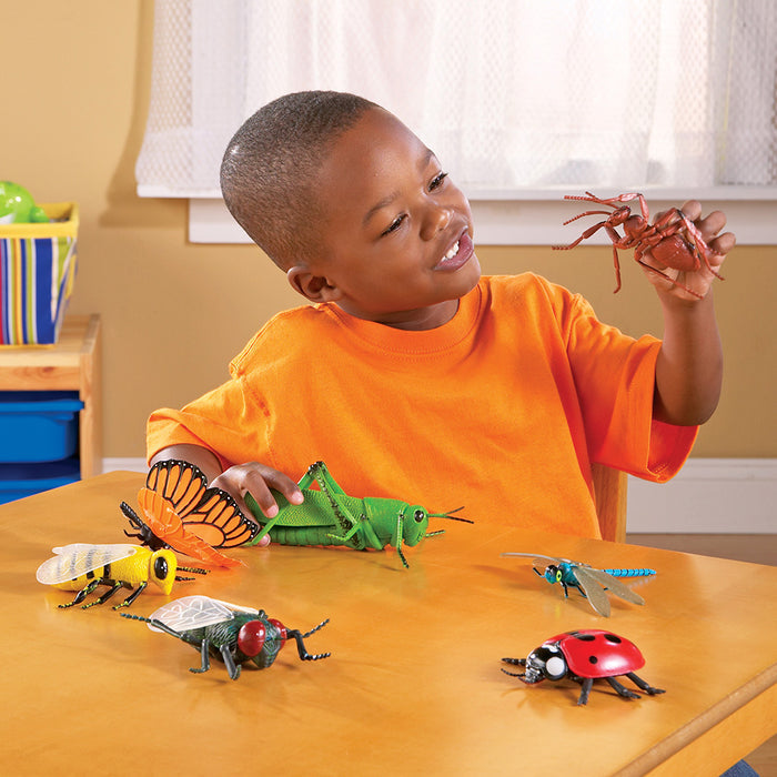 Child playing with toy insects on a table