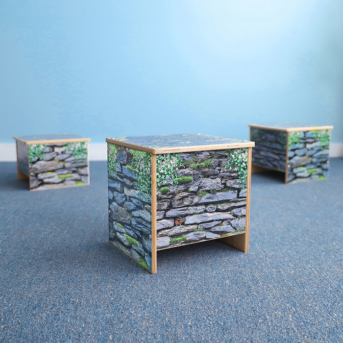 Three small benches with stone wall design on a blue surface and light blue background