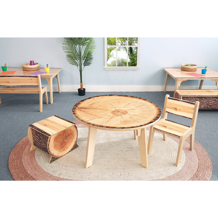Children's wooden play table and chairs in a classroom setting with a plant and window in the background.