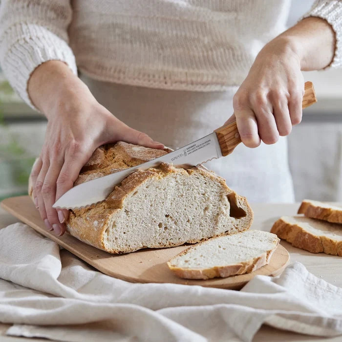 Opinel Parallele Serrated 8" Bread Knife slicing through bread with a model holding it at Addison West