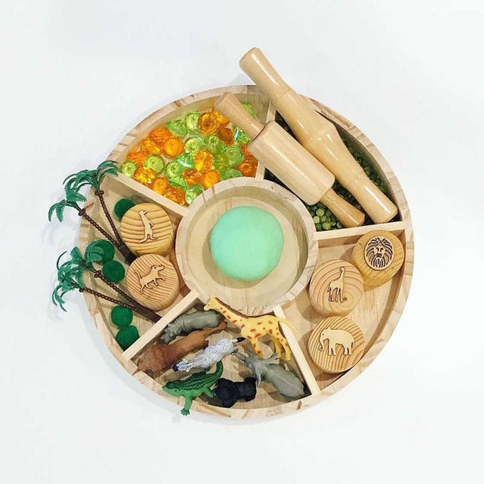 Wooden toy set with animals, plants, and a magnifying glass on a white background