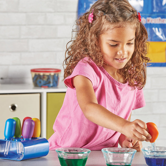 Child in a pink shirt playing with colorful toys in a kitchen setting