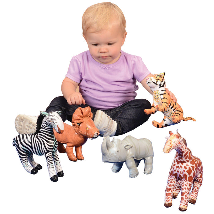 Baby playing with soft jungle animal figures on a white background