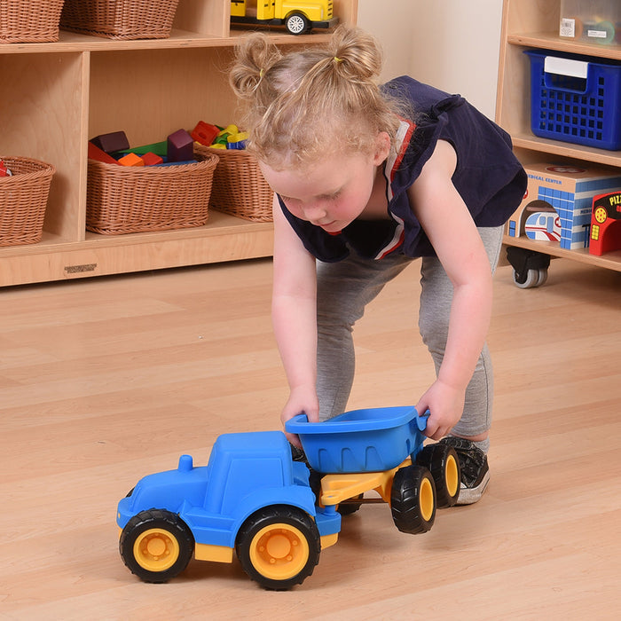 Child playing with Toy dump truck with blue body on hardwood floor