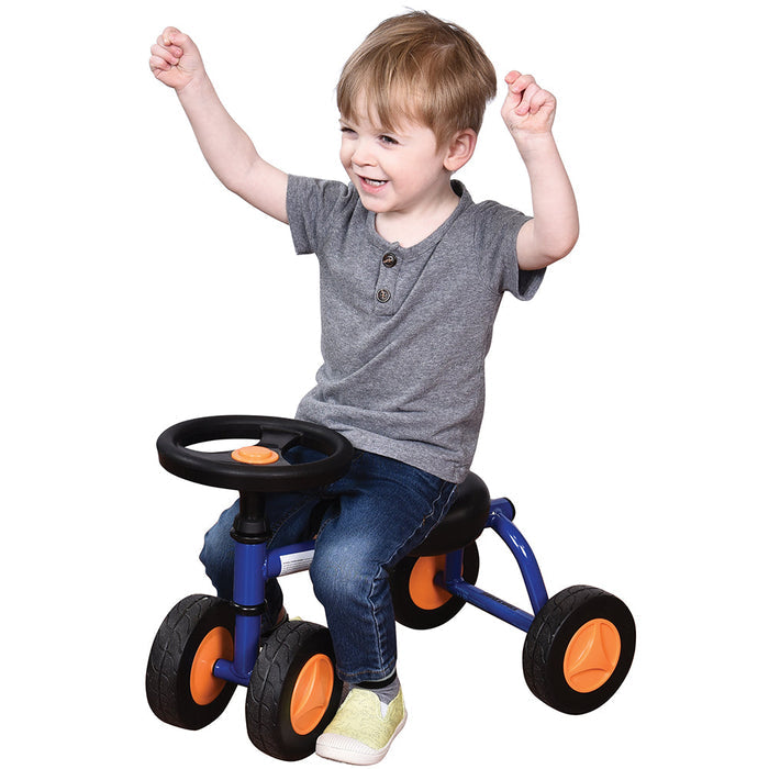Toddler in gray shirt seated on blue trike with white background