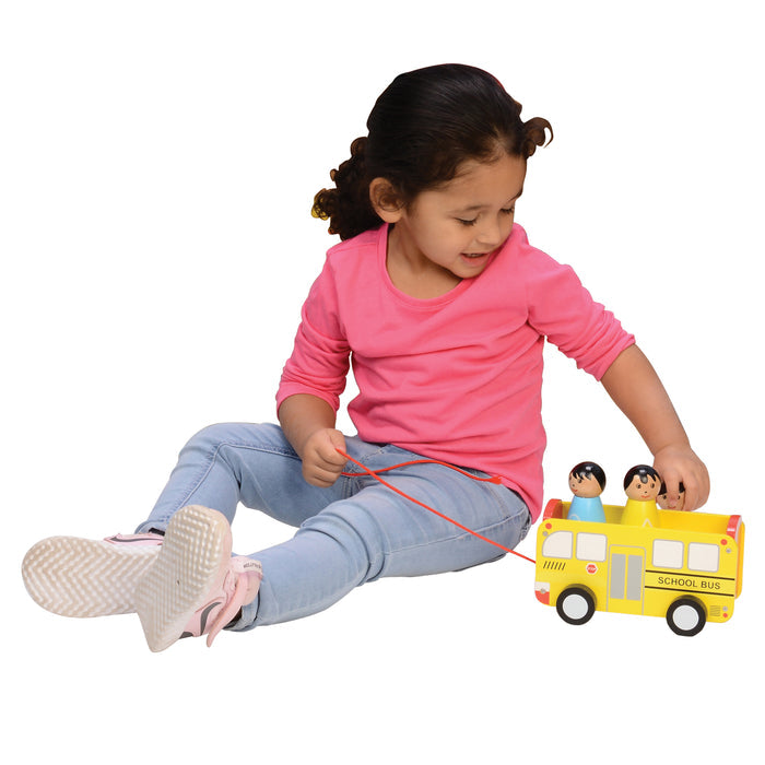 Child playing with a toy school bus on a white background