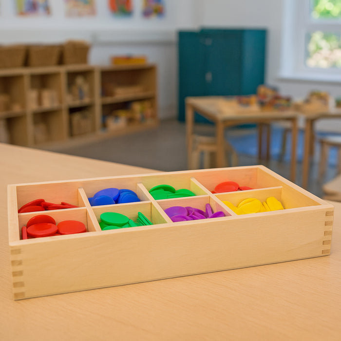 Colorful plastic blocks in a wooden tray on a table in a classroom setting