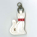A white cat-shaped zip pull with a red collar and a metal loop at the top.